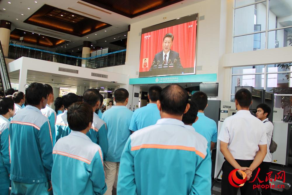 10月18日上午，海南三亚国际邮轮港干部职工和游客一起观看党的十九大开幕会。人民网吉羽 摄
