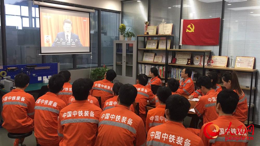 10月18日上午，在河南郑州中铁工程装备集团有限公司盾构总装车间“大国工匠”工作室内，工友们正在观看十九大开幕会。人民网慎志远 摄