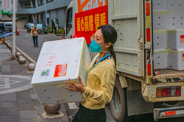 三亞市天涯區網格人員瘦弱的身體抱起重重的箱子，與后勤保障人員無縫對接，做好后勤防線保障。