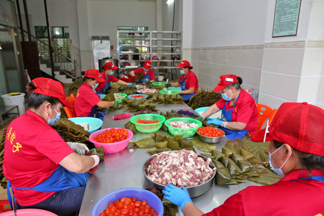 儋州五哥食品有限公司工人正在包粽子。?