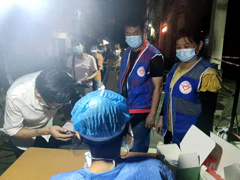 夜幕降临，志愿者们协助医护人员开展核酸采样。共青团龙华区委供图