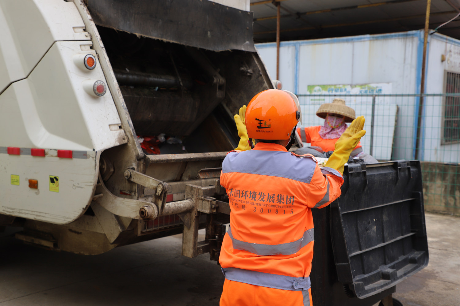 环卫工人利用垃圾收集车运送生活垃圾。