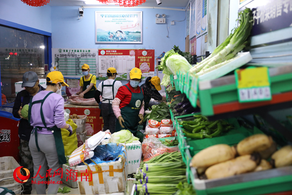 在海口市菜篮子平价超市，员工将运进来的蔬菜归类整理。人民网 孟凡盛摄
