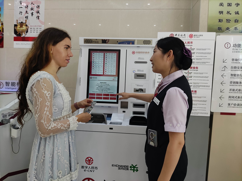 中国银行工作人员在向Ms.Anastasiia介绍数字人民币兑换机的使用方法