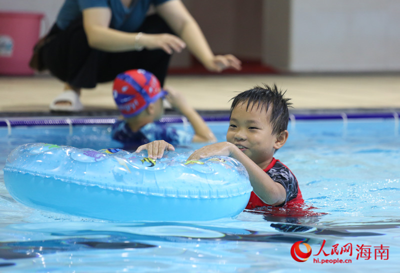 在三亚市吉阳区丹州小学游泳馆内，一名学生正借助泳圈学习游泳。人民网 牛良玉摄