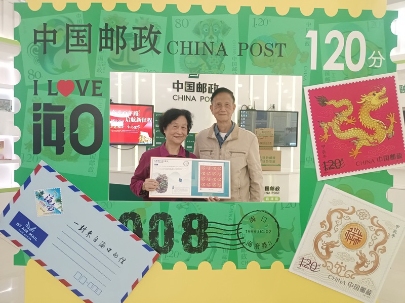 在海口市海府路买到龙年邮票的邮迷在“打卡墙”上拍照留影（李慧摄）
