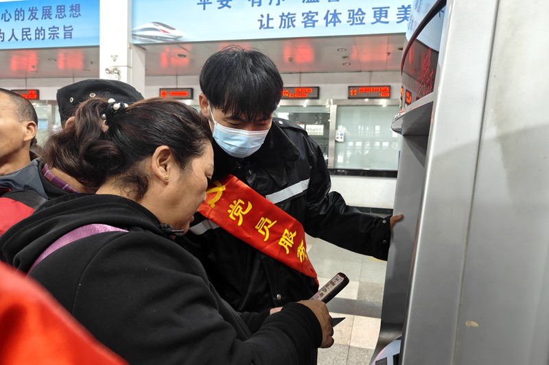 在海口站，志願者幫助旅客購票。唐璐璐攝