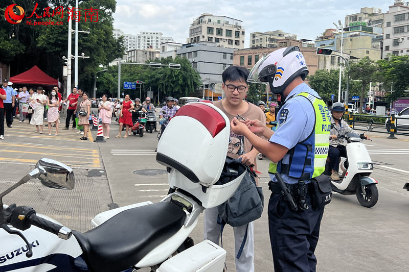 在海南省農墾中學考點，交警載著考生取回身份証后返回考點。 人民網記者 李學山攝