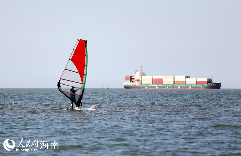 帆板与货轮同框，形成一道靓丽的风景线。人民网记者 符武平摄